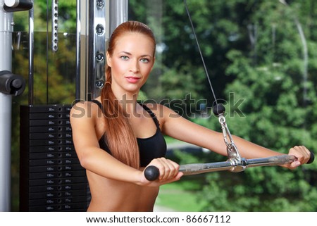closeup portrait of young woman doing workout on exercise machine in gym