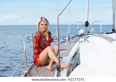 picture of sexy young woman in red dress sitting on the yacht