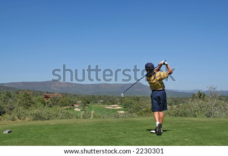 Young golfer hitting a golf ball tee shot in the mountains
