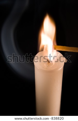 A picture of a match being igniting by a burning candle.