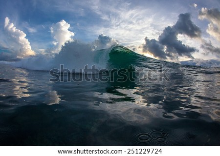 A huge wave for surfing on the background of beautiful sunset and clouds. The photo was taken from the water in the Indian Ocean island of Mauritius