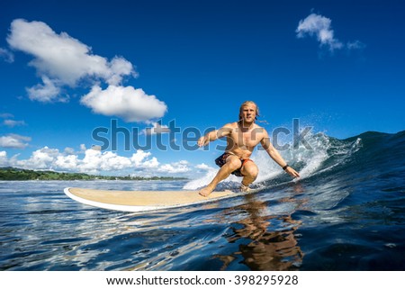 Surfer with long white hair rides in the big ocean wave in Mauritius Island, Indian Ocean