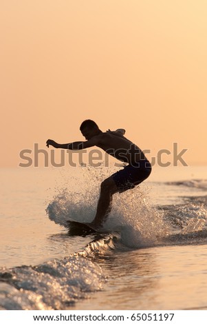 a young man riding on surf  on the waves at sunset
