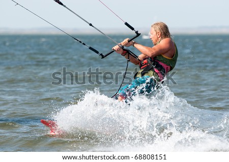 young tanned kiter with long white hair  kiting in the surrounding of sea spray