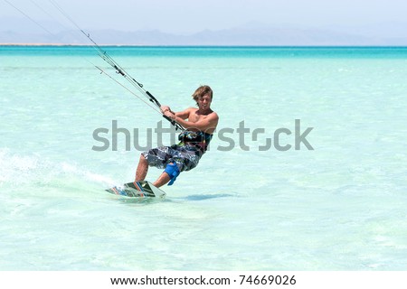 young tanned kiter with long hair  kiting in the surrounding of  turquoise sea spray