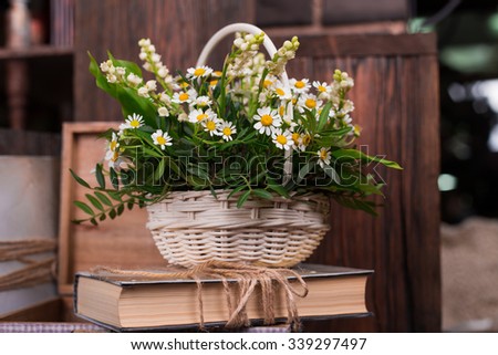 Chamomile decor composition with books and box on the old brown wood table. Selective focus with bokeh.