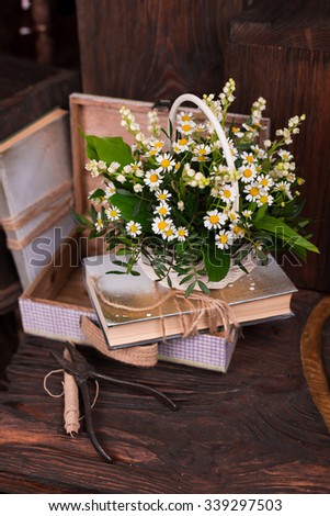 Chamomile decor composition with books and box on the old brown wood table. Selective focus with bokeh.