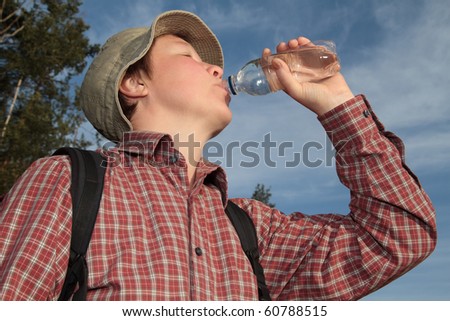 woman traveling with a backpack in the woods, drinking mineral water