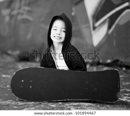 Young boy with skateboard against a graffiti wall