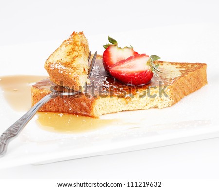 French toast with syrup and strawberry on a white plate.