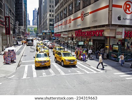 New York City, NY - June 28, 2014:  Intersection in Times Square with taxi cabs, pedestrians and store fronts in New York City, NY on June 28, 2014.