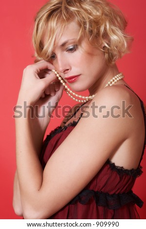 Blond model with a pearl necklace on a neck and in a beautiful evening black dress