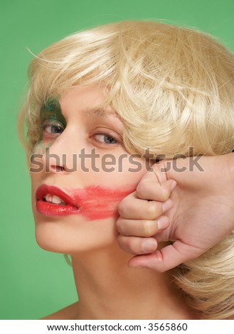A beautiful girl in a wig. She smears lipstick on the face.Photo N1
