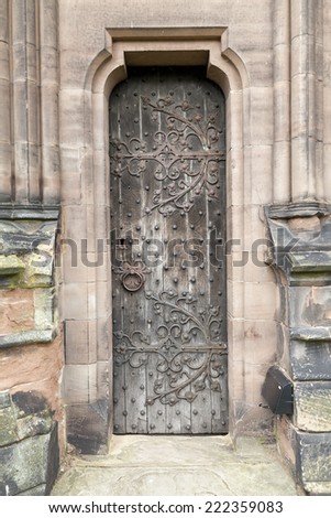 Narrow Medieval oak door with original rusting metal leaf pattern, square head nails, and door handle.
