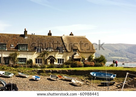 Row Of Cottages By The Sea. An Idyllic scene by the sea with thatched cottage boats and mountains.