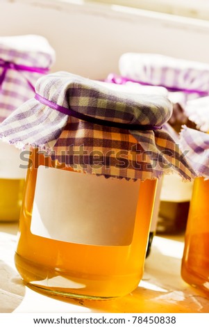 Home made honey in a jar with blank white label. Natural  back lighting from window.