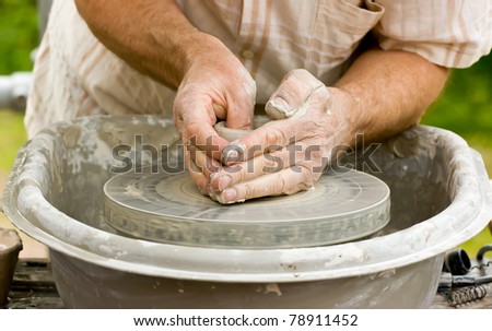 Close-up of potter\'s hands turning clay on a potter\'s wheel.