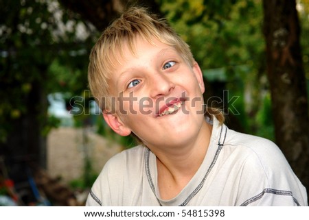 Happy boy builds smileys in the garden under the apple tree