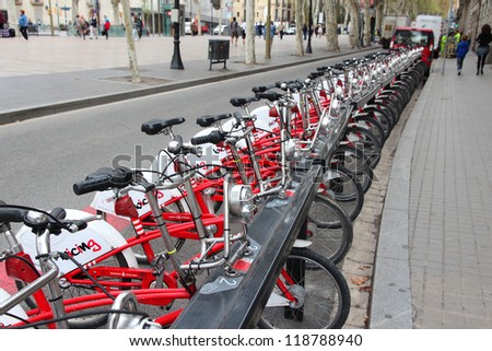 BARCELONA, SPAIN - NOVEMBER 6: Pedestrians walk by Bicing bikes on November 6, 2012 in Barcelona, Spain. Bicing is one of oldest city bike networks with 400 stations and 6,000 bicycles.