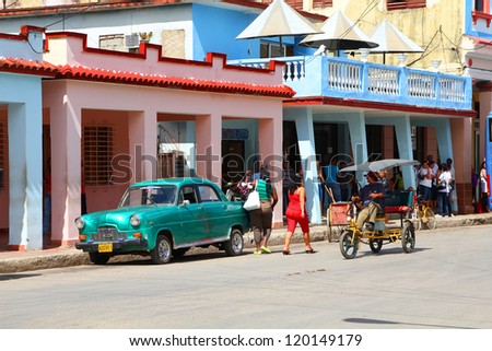 MORON, CUBA - FEBRUARY 19: People walk past old car on February 19, 2011 in Moron, Cuba. Recent change in law allows the Cubans to trade cars again. Cars in Cuba are very old because of the old law.