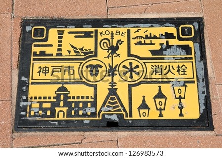 KOBE, JAPAN - APRIL 24: Most popular landmarks are presented on a sewer cover on April 24, 2012 in Kobe, Japan. Decorative and colorful sewer covers are typical for cities in Japan.