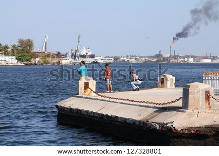 HAVANA - FEBRUARY 26: Cubans fish on February 26, 2011 in Havana. In background refinery air pollution is visible. Government in 2012 confirmed sharp rise in air pollution and acid rains in Cuba.