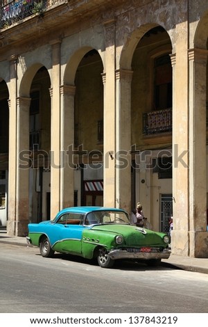 HAVANA - FEBRUARY 27: People walk past old car on February 27, 2011 in Havana, Cuba. Recent change in law allows the Cubans to trade cars again. Most cars in Cuba are very old because of the old law.
