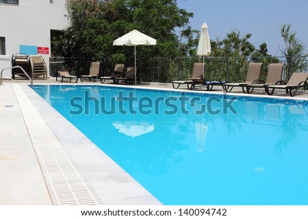 Generic vacation resort in Crete island in Greece. Swimming pool sun tanning chairs.