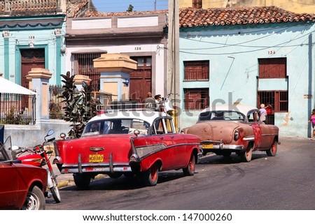 MATANZAS, CUBA - FEBRUARY 22: People walk past old cars on February 22, 2011 in Matanzas, Cuba. New change in law allows Cubans to trade cars. Cars in Cuba are very old because of the old law.