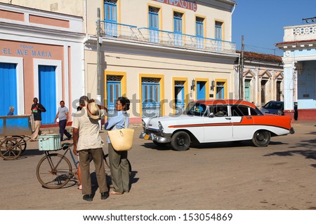 REMEDIOS, CUBA - FEBRUARY 21: People walk past old car in the street on February 21, 2011 in Remedios. Recent change in law allows the Cubans to trade cars after it was forbidden for many years.