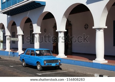 SANTIAGO, CUBA - FEBRUARY 8: People walk past old car on February 8, 2011 in Santiago. Recent law change allows the Cubans to trade cars again. Most cars in Cuba are very old because of the old law.