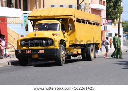 SANTIAGO, CUBA - FEBRUARY 10: People walk past old truck on February 10, 2011 in Santiago, Cuba. Recent change in law allows Cubans to trade cars again. Old law resulted in old fleet of private cars.