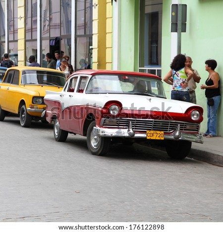 Camaguey, Cuba - February 17, 2011: People Talk By Vintage Russian And American Cars Parked In Camaguey. Cuba Has One Of The Lowest Car-Per-Capita Rates (38 Per 1000 People In 2008).