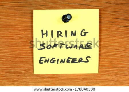 Sticky note with employment opportunity message - hiring software engineers. Bulletin board with computer jobs.