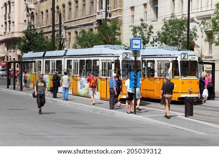 BUDAPEST, HUNGARY - JUNE 19, 2014: People board orange tram in Budapest. It is part of BKK public transport system which serves 1.4 billion annual rides (2011).