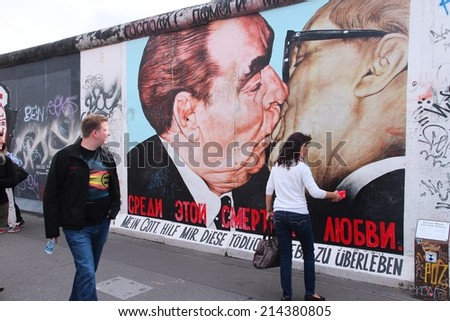BERLIN, GERMANY - AUGUST 26, 2014: People visit urban art of East Side Gallery in Berlin. Part of former Berlin Wall is covered in art by more than 100 artists since 1990.