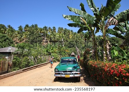 BARACOA, CUBA - FEBRUARY 12, 2011: People walk by oldtimer car in Baracoa, Cuba. Cuba has one of the lowest car-per-capita rates (38 per 1000 people in 2008).