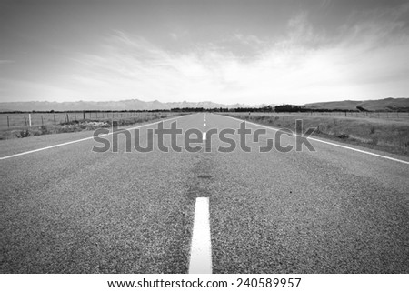 New Zealand. Straight road. Plains and mountains in Canterbury region. Black and white tone - retro monochrome color style.