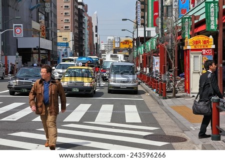 TOKYO, JAPAN - APRIL 13, 2012: Man crosses street in Asakusa district, Tokyo. Asakusa is one of the oldest districts of Tokyo, capital city and largest urban area of Japan (35 million people).