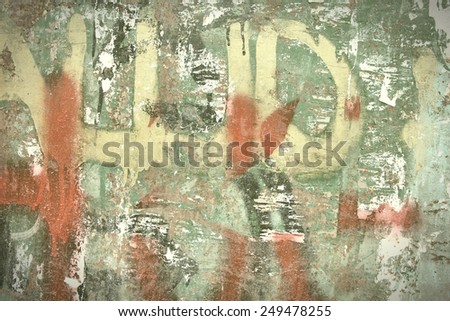 Grunge urban background - metal wall with torn posters and graffiti vandalism. Cross processed color tone - retro image filtered style.