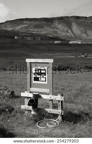 RV camping sewage dump station at a campground in Iceland. Focus on the sign. Black and white monochrome tone.