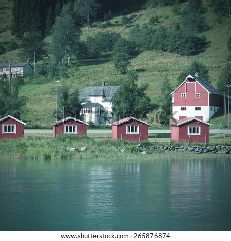 Norway, Sogn of Fjordane county. Small red cabins next to Nordfjord in Olden. Vintage style photo color.