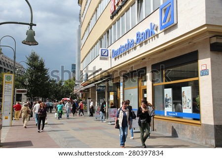 BERLIN, GERMANY - AUGUST 27, 2014: People walk by Deutsche Bank branch in Berlin. Deutsche Bank is one of largest banks in the world with 98,200 employees (2013).