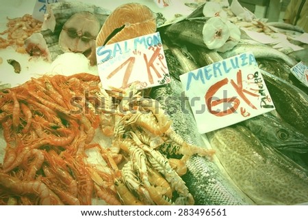 Salmon, shrimps and hake fish at a food market in Valencia, Spain. Retro filtered style image.