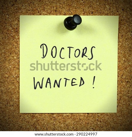 Yellow sticky note pinned to an office notice board. Doctors wanted - employment and medical career recruitment message.
