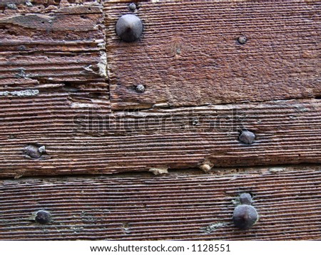 Close-up on a old brown painted wooden gate - decaying wood and rusty nails. Nice background pattern or texture - geometric lines and shapes.