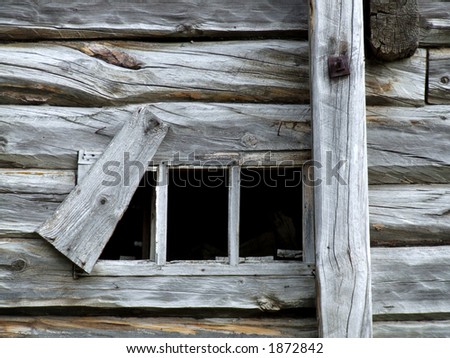 Old small window in wooden house. Wooden rural cottage and a small dark window.