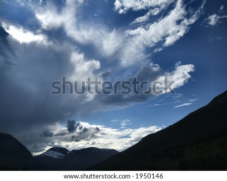 Blue sky with clouds and mountain outlines.