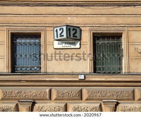 Two old windows, street number and the street name written Cyrillic alphabet (Russian city).