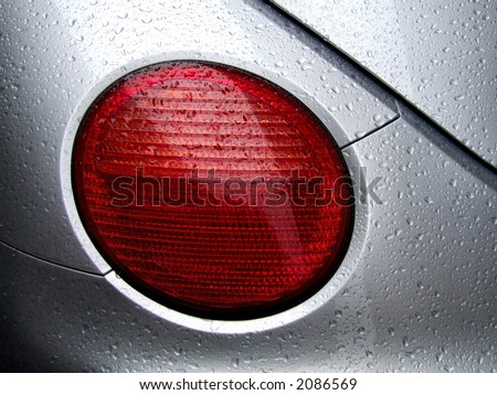 Beautiful, new and shiny car with silver paint. Water drops on the hood. Car lamp.